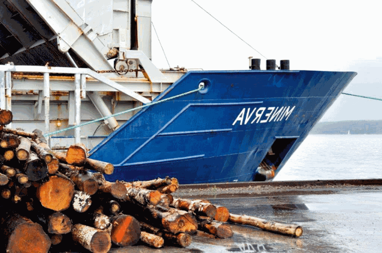 Boat docked by pile of timber
